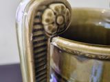 a vase that has a handle on it on a table