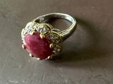une bague sertie d'une pierre rouge, posée sur une table