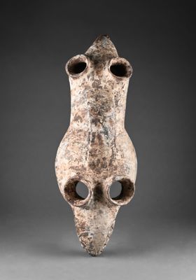 un gros plan d'un vase troué posé sur une surface grise