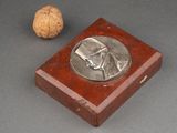 a small wooden box with a silver medal on it