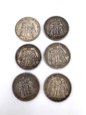 six silver coins of different sizes and shapes on a white surface