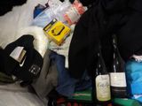 a pile of clothes and bottles of wine on a bed