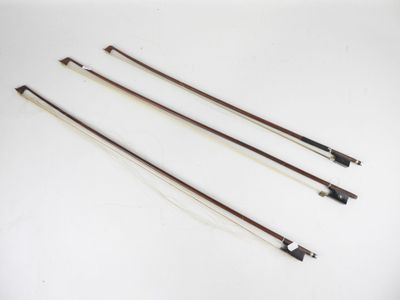 un ensemble de quatre archets de violon posés sur une surface blanche