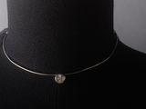 a close up of a mannequin wearing a necklace with a coin on it