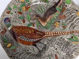 a decorative plate with a bird on it on a table