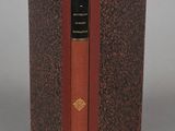 an old book with a red cover sitting on top of a table