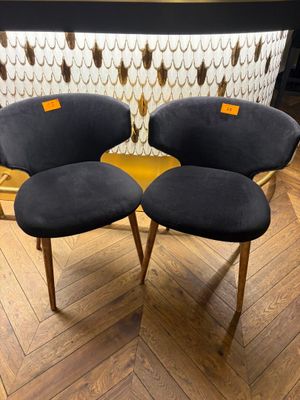 two black chairs sitting on top of a wooden floor next to a wall