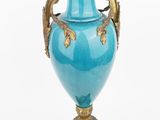 a blue vase with a gold handle on a stand