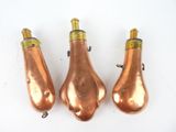 trois lampes de couleur cuivrée posées sur une surface blanche