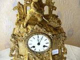 une horloge en or posée sur une table recouverte d'une nappe blanche