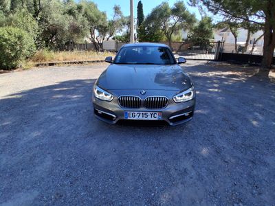 La BMW est garée sur le bord de la route, devant des arbres.