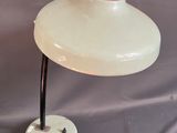 une photo d'une lampe de table blanche posée sur un pied en métal