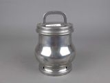 silver metal container with handle and handle on a gray surface