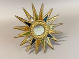 a gold starburst with a mirror in it on a table