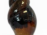 un objet de couleur marron et noire en forme de coquillage posé sur une surface blanche