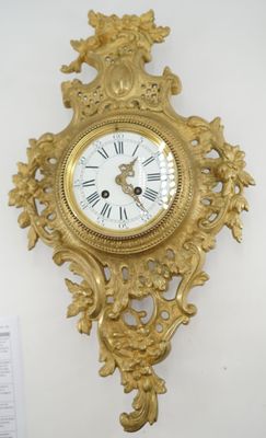 une horloge en or accrochée au mur à côté d'une feuille de papier