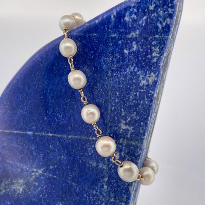 pearl necklace on a blue stone with a gold plated chain