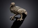 une figurine d'oiseau en argent posée sur une surface noire
