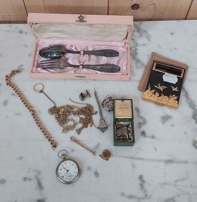 une table sur laquelle sont posés plusieurs objets, notamment une montre, une montre de poche, une chaîne de montre, une montre de poche et une montre