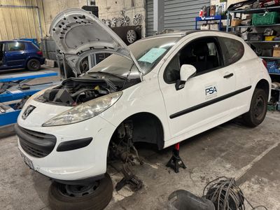 une petite voiture blanche, le capot ouvert, dans un garage