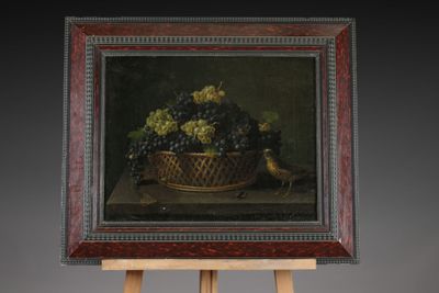 a picture of a painting of grapes in a basket on an easel