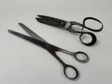 two pairs of scissors sitting on a white surface