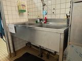 un lavabo en acier inoxydable dans une salle de bains aux murs carrelés