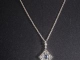 a woman wearing a necklace with a diamond pendant on it