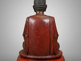 a wooden buddha statue sitting on top of a wooden base