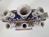a blue and white vase that has five cups on it