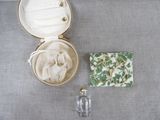 un petit sac à main et un petit flacon de parfum posés sur une table