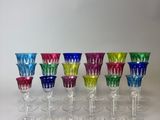 seven colorful wine glasses lined up in a row on a white surface