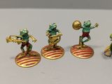 four figurines of frogs playing with a basketball ball