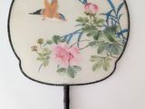 a fan with a painting of a bird and flowers on it