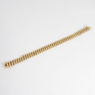 gros plan d'un bracelet en or sur une surface blanche