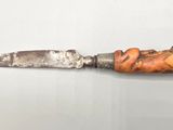 an old knife with a carved handle on a white surface