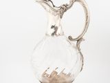 a glass pitcher with sand in it on a white surface