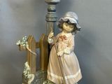 une figurine représentant une petite fille debout à côté d'un lampadaire