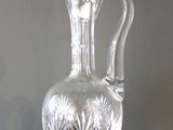 un vase en verre transparent muni d'une anse, posé sur une table noire