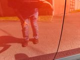 a reflection of a man walking on the side of a car
