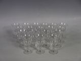 six clear wine glasses are lined up on a white surface
