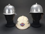 pair of firemen ' s helmets on mannequin heads against a gray background
