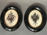two framed pictures of flowers are on a wall in a black frame