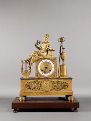 une horloge en or avec une femme assise dessus