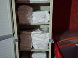 towels are stacked on a shelf next to a refrigerator in a room