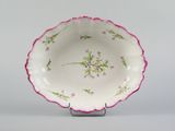 a white bowl with pink flowers on it on a stand