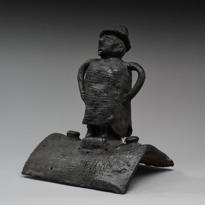 statue représentant un homme debout sur un morceau de bois, coiffé d'un chapeau