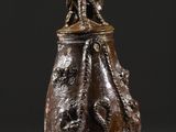 une image représentant un vase marron surmonté d'un oiseau