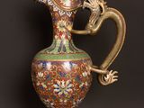an image of a vase with a dragon handle on a wooden table