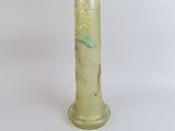 a green vase with a bird on it sitting on a table